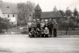 Zdjęcie dzieci ze Swornegaci na tle drewnianej świątyni znajdującej się obecnie we Wdzydzach Kiszewskich